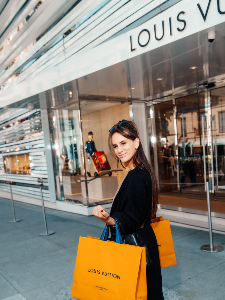Vulgar Yogi founder holding Louis Vuitton shopping bags outside Louis Vuitton 273 North Rodeo Drive Beverly Hills